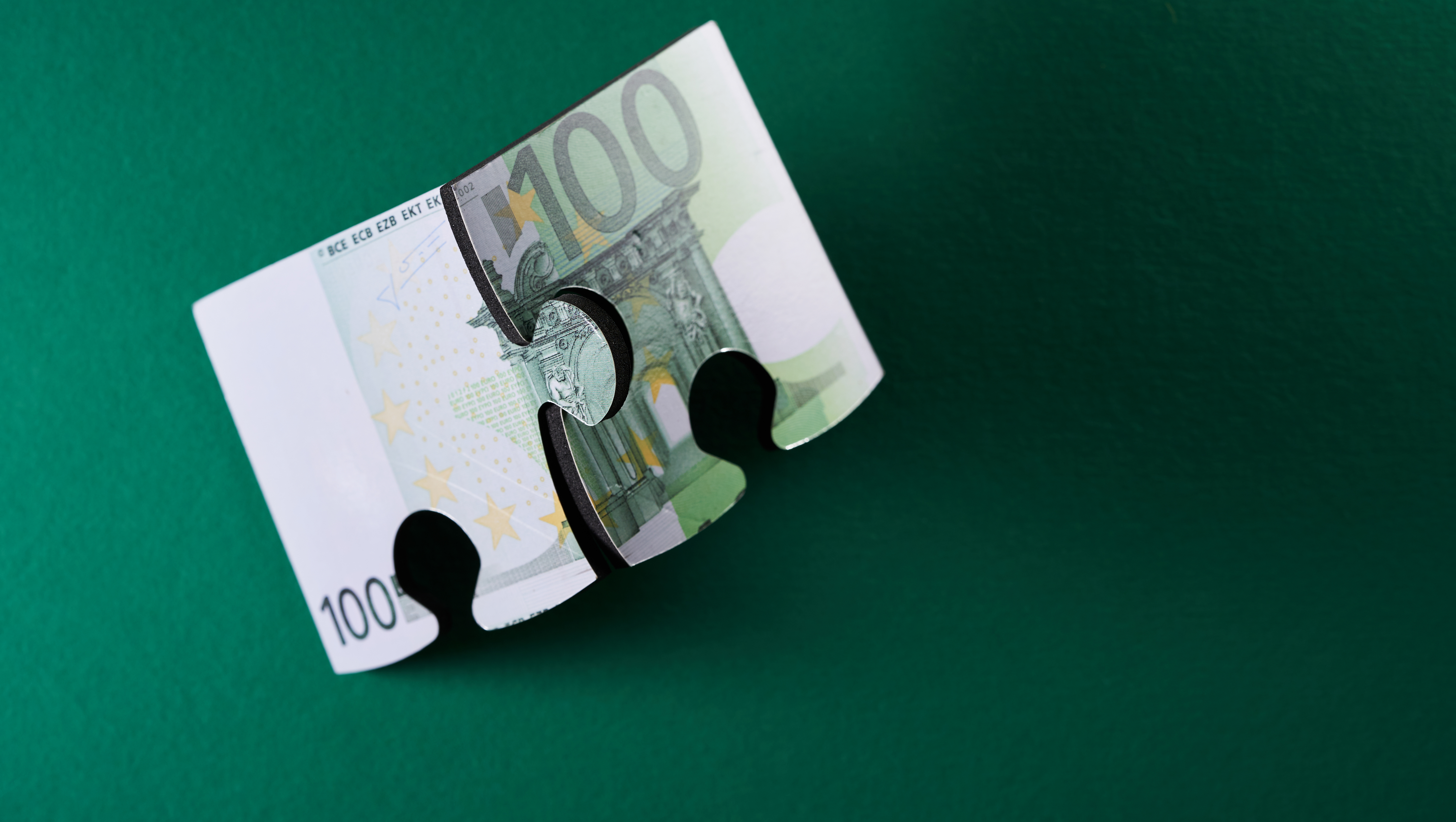 Puzzle der Euro-Währung vor grünem Hintergrund