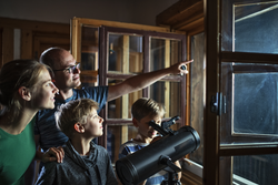 Vater und drei Kinder benutzen das astronomische Teleskop, um den Mond und die Sterne zu beobachten. Nikon D850