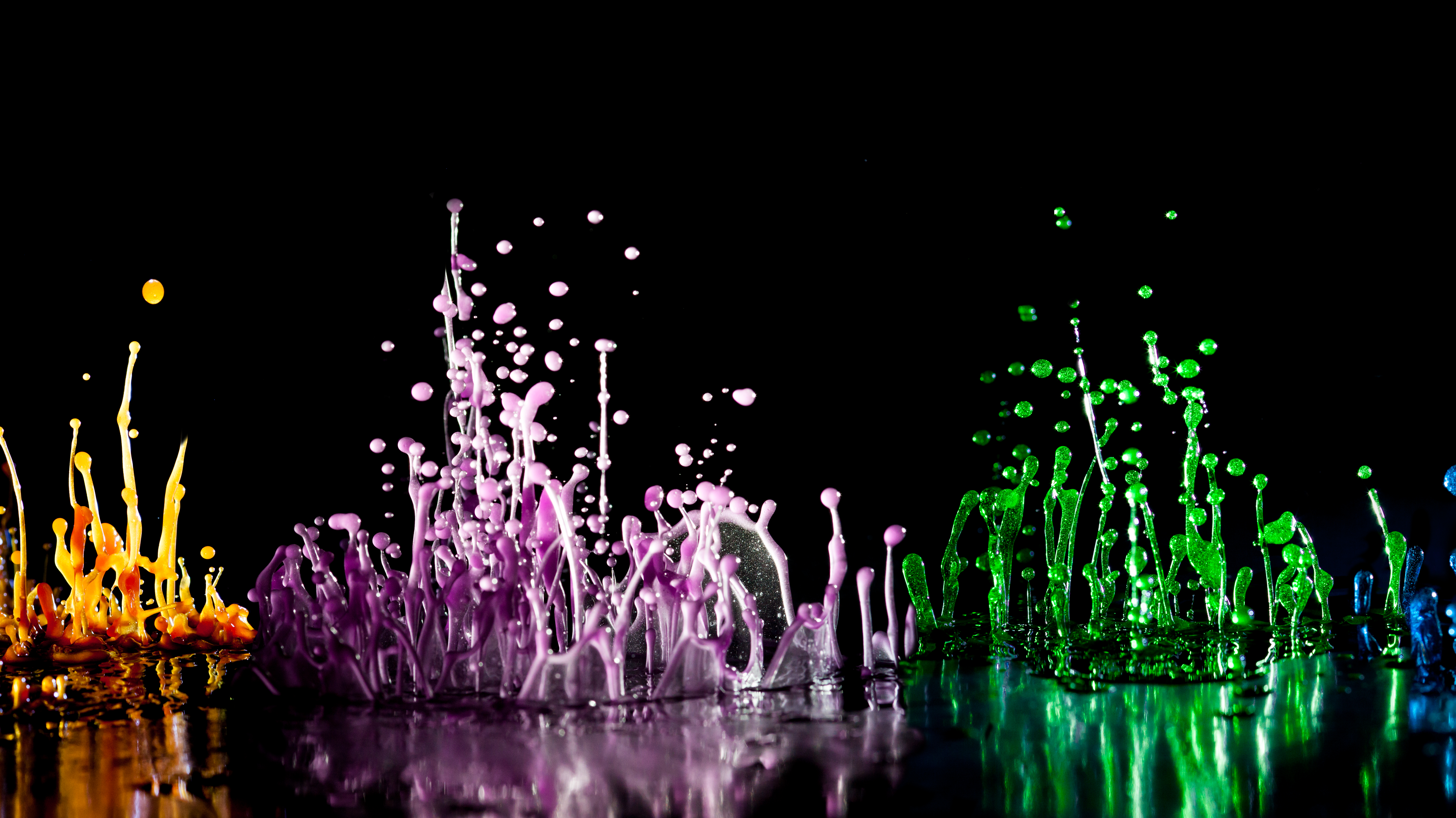 Tanzende farbige Wassertropfen auf schwarzem Hintergrund