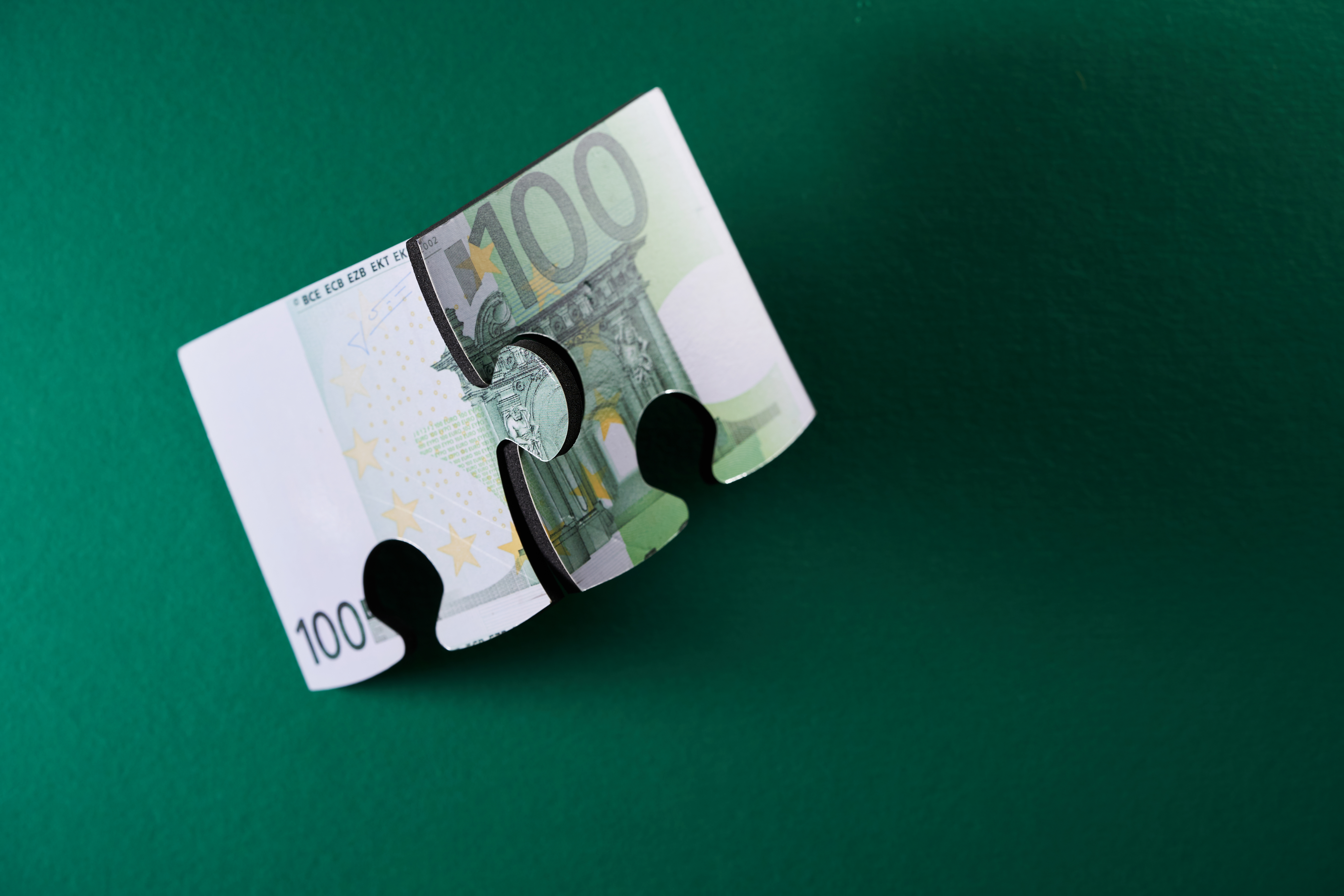Puzzle der Euro-Währung vor grünem Hintergrund